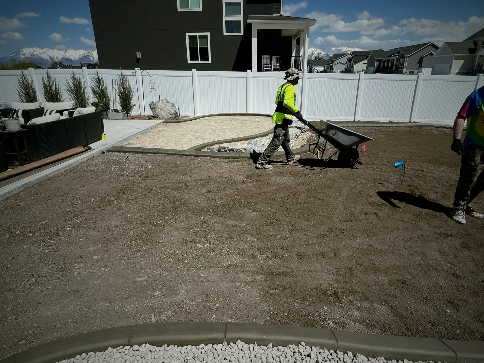 A crew spreading topsoil in a backyard with a wheelbarrow