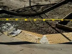 Wood forms and stakes on a gravel base, caution tape across them